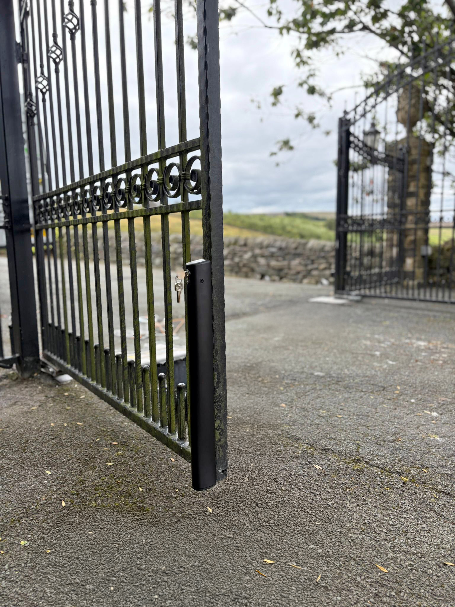 This image shows large wrought iron automated swing gates, with drop bolts.
