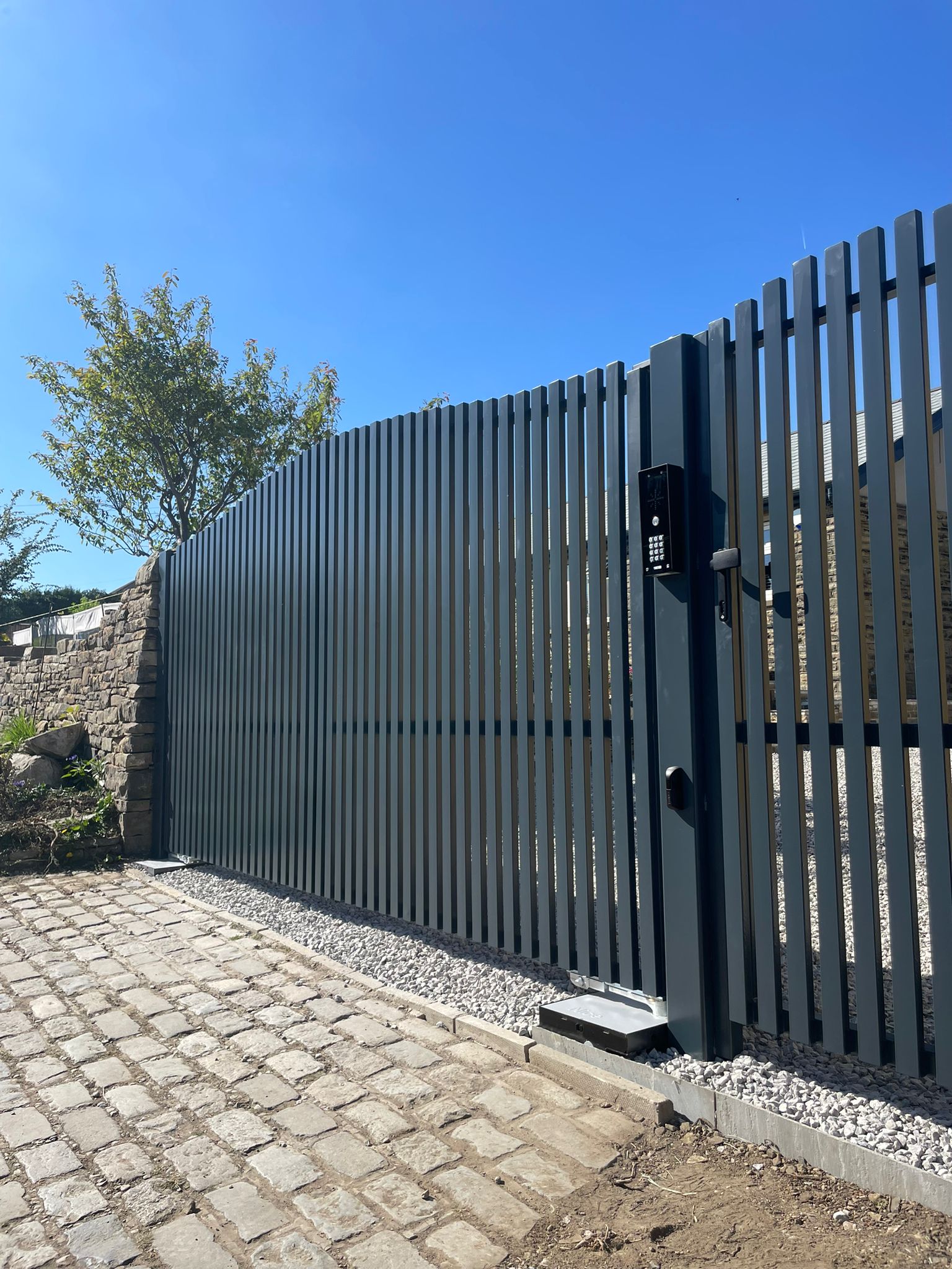 This image shows an automated double swing gate, with pedestrian gate, intercom and safety sensor.