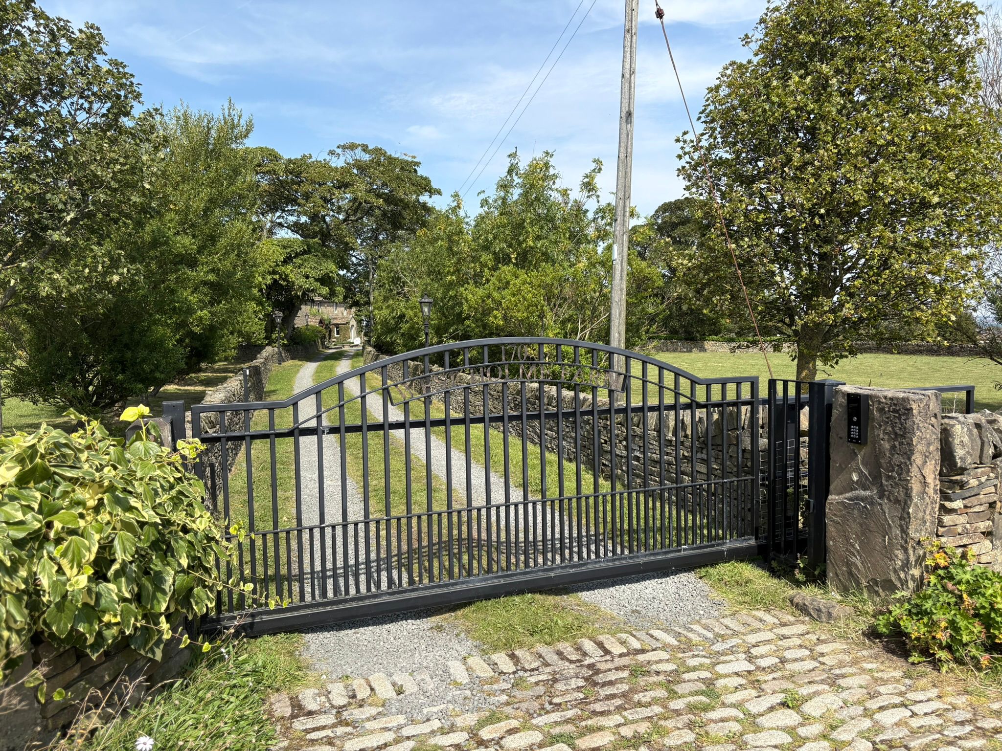 The image shows a repaired automated sliding gate with AES intercom system.