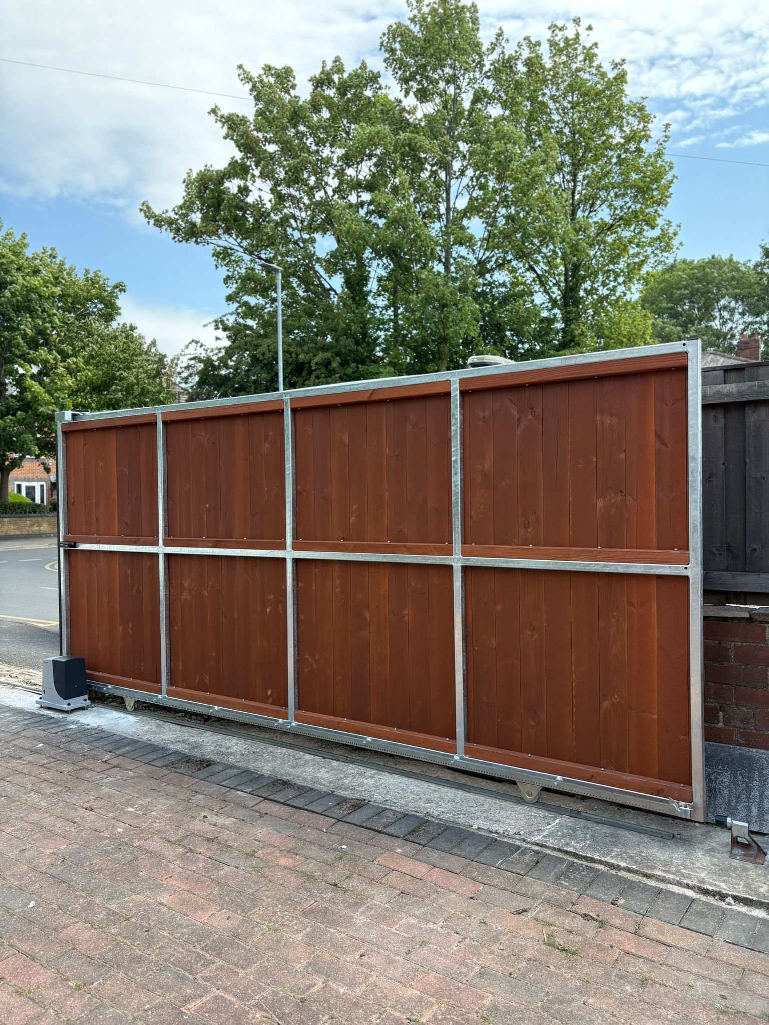 This image features a large automated gate, using a Nice Robus sliding gate operator, and SENTIR safety strips.