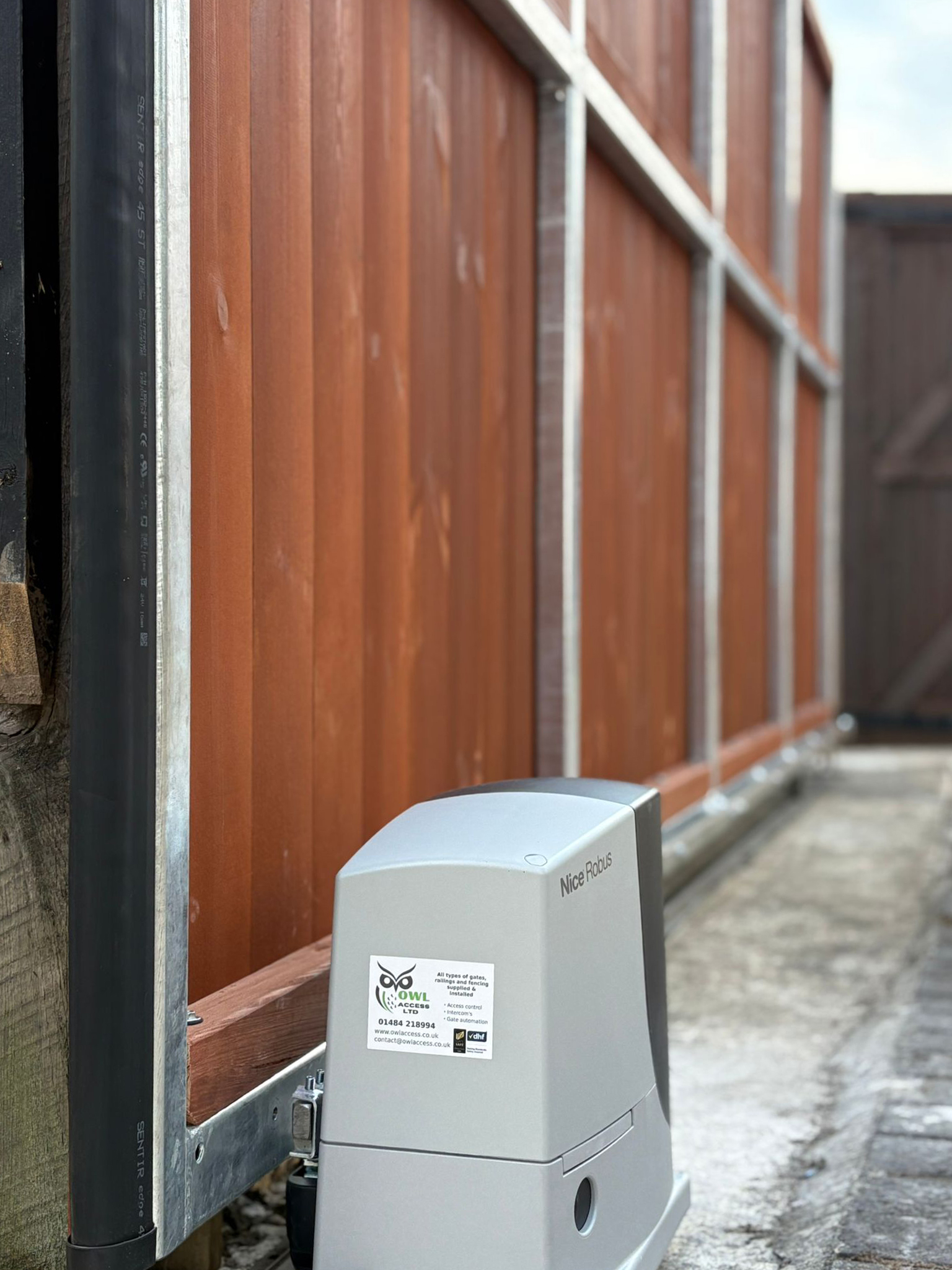 This image features a large automated gate, using a Nice Robus sliding gate operator, and SENTIR safety strips.