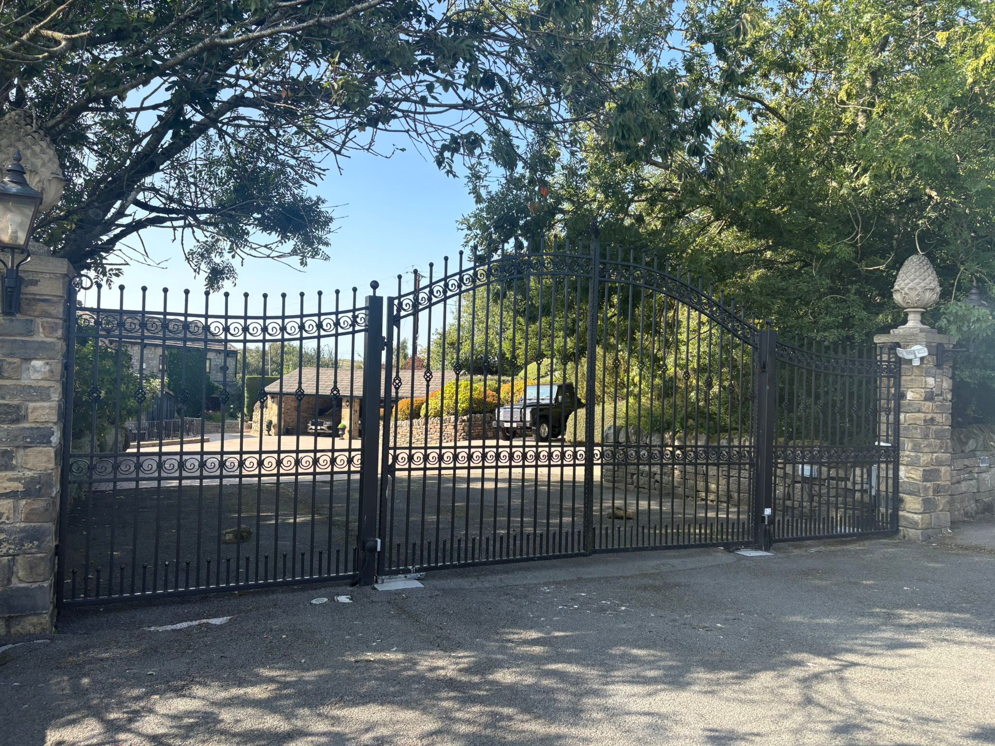 Large ornamental wrought iron automated gates featuring a newly installed electronic drop-bolt for enhanced security.