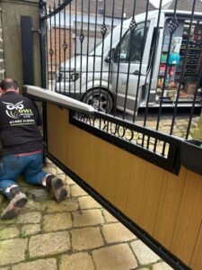 Professional technician performing a safety service on a set of automated driveway gates.