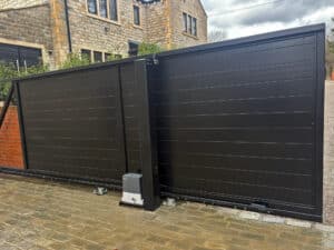 A side profile view of a black sliding gate in the partially open position, highlighting the Beninca automation motor and the sleek horizontal slat design.