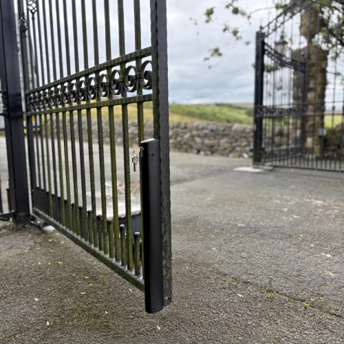 This image shows large wrought iron automated swing gates, with drop bolts.